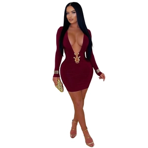 Détail d'une robe moulante bordeaux avec une boucle serpent dorée et un décolleté en V plongeant