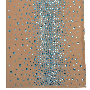 Détail de la robe en mesh avec strass bleu clair en dégradé sur tissu beige clair