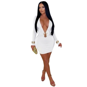 Détail de la robe mini blanche à manches longues avec décolleté en V profond et boucle dorée