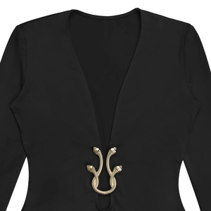 Détail de la boucle serpent dorée sur robe noire à col en V profond et texture écaillée
