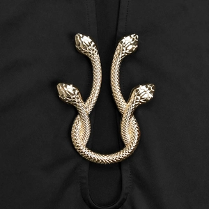 Détail de l'ornement serpent doré sur une robe noire sexy avec col en V profond