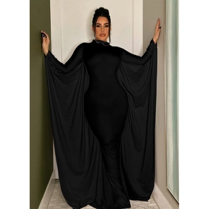 Detail of dramatic batwing cape sleeves on a slim-fit black maxi dress with a turtleneck