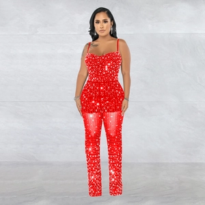 Detailed close-up of sparkling white rhinestones on sheer red mesh party jumpsuit fabric