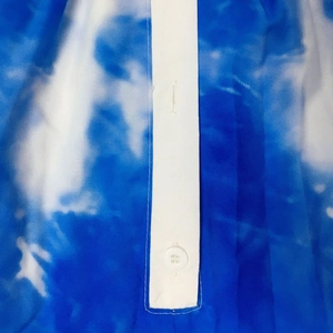 Detail von blau-weißem Batikstoff mit weißem Knopf und Nahtdetail an der Knopfleiste