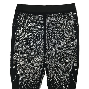Detail of black stretch leggings with dense silver rhinestones in a striped pattern