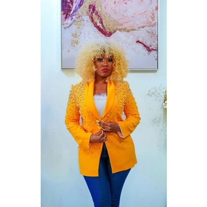 Detail view of bright yellow blazer with dense white pearl embellishments on the lapel
