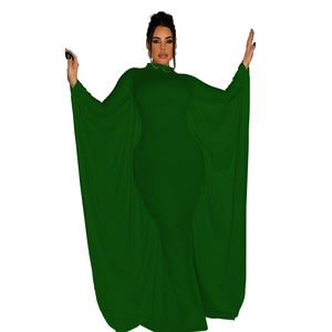 Macro detail of high-neck dark green bodycon dress featuring dramatic batwing cape sleeves