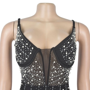 Détail d'un haut noir à col en V avec patchwork en résille, perles et strass