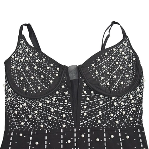 Détail des ornements en strass et perles sur une robe noire en tulle et résille
