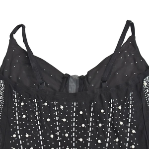 Détail de la robe en maille noire avec strass scintillants et ornements en perles