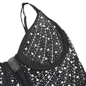 Détail d'une robe caraco noire ornée de perles décoratives et de strass brillants
