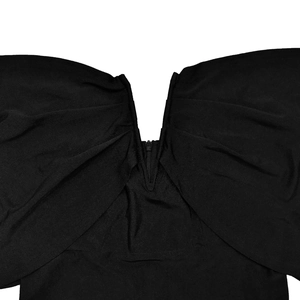 Dettaglio di un abito nero con spalle scoperte, scollo a V profondo e cerniera invisibile