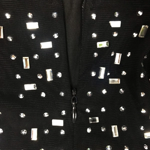 Detail of black knit fabric featuring shimmering silver rhinestones and a central zipper
