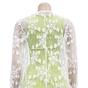 Detail of white lace cardigan showing intricate hollow floral pattern and sheer mesh texture