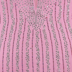 Détail de tissu en maille rose orné de strass brillants et d'une broderie de perles élégante