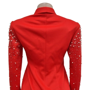 Macro detail of white pearls and rhinestones on the sleeves of a red blazer jacket
