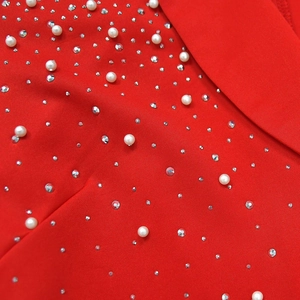 Detail of red blazer fabric featuring white pearls and shimmering silver rhinestones