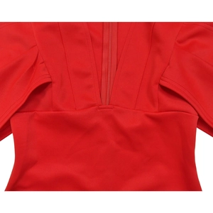 Détail d'une robe rouge à col en V avec plis structurés et découpes aux épaules