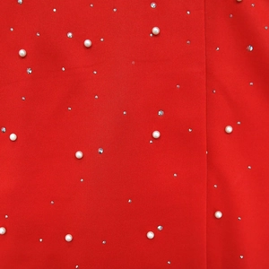Detailed view of red fabric blazer featuring elegant white pearls and rhinestone embellishments