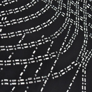 Detail of silver rhinestones and mesh tassels on black fabric for women evening dress