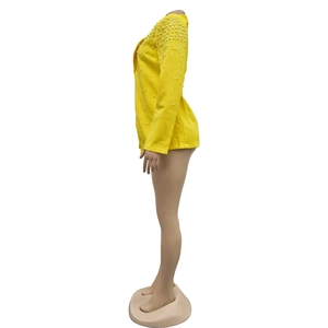 Detail of elegant yellow blazer featuring decorative white pearls on shoulders and sleeves