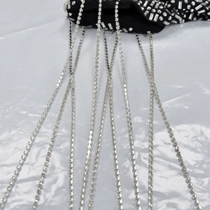 Dettaglio di eleganti frange di strass argento su tulle nero per abito da festa