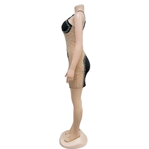 Détail d'une mini robe en mesh avec strass et fausses perles sur tissu noir chic