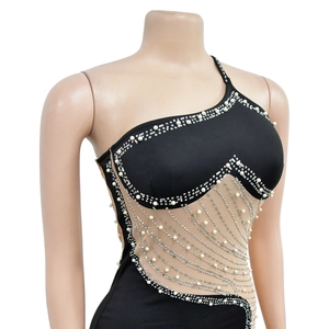 Détail de la robe noire asymétrique ornée de perles blanches et de strass argentés