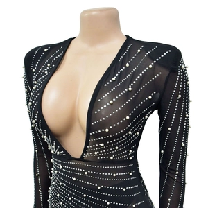 Detailed view of black mesh dress featuring deep V-neck with white pearls and silver rhinestones