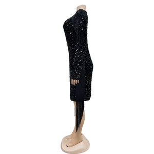 Detail view of black sequin mini dress featuring long sleeves and hanging side fringes