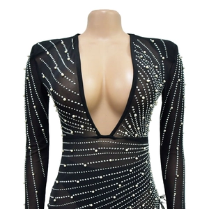 Detail of black mesh bodysuit with deep V-neck featuring silver rhinestones and white pearls