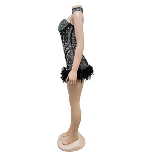 Detail of black mesh jumpsuit with rhinestone patterns and feather trim at the hem