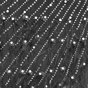 Detailed macro shot of black mesh fabric with rhinestones, pearls, and feather fringe