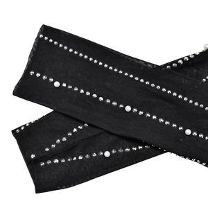 Detail of mesh sleeves with sparkling rhinestones and white pearls on black fabric