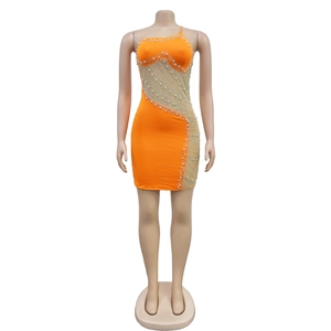 Détail de robe orange avec panneau en mesh, perles et strass scintillants sur le côté
