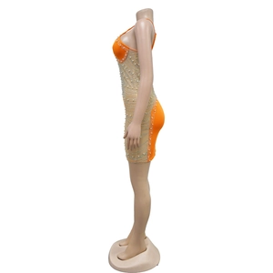 Détail d'une robe moulante orange avec empiècements en résille et broderie de strass