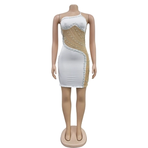 Détail d'une mini robe moulante blanche avec empiècements en résille, perles et strass