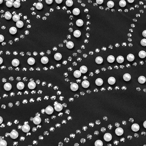 Vista macro di perle bianche e strass applicati sul tessuto nero dell'abito elegante
