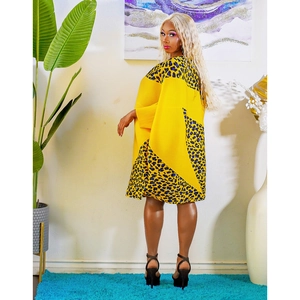 Detail of a bright yellow dress featuring blue leopard print patchwork on shoulders and hem
