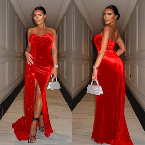 Détail d'une robe de soirée rouge en velours et sequins avec fente haute et traîne
