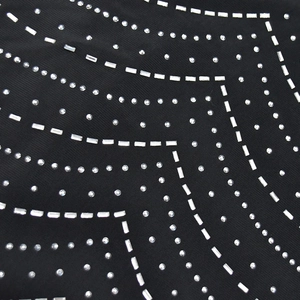 Dettaglio del vestito in rete nera con strass scintillanti e borchie in metallo argento