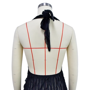 Detailed view of black halter neck dress with pleated hem and backless design on mannequin