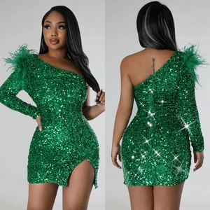 Detail of emerald green sequin dress featuring one-shoulder feathers and side slit