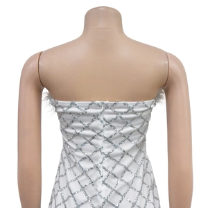 Detail showing white sequin tube dress with silver diamond pattern and feather trim