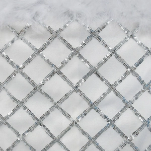 Close-up of white sequined diamond pattern dress featuring elegant feather trim details