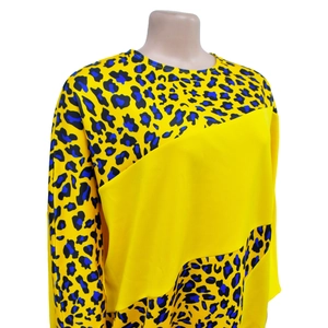 Detail of long sleeve dress featuring vibrant yellow panels and blue leopard print accents