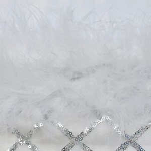 Macro detail of luxury white ostrich feathers and silver sequins on mesh fabric