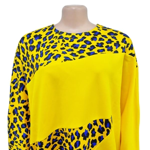 Close-up of bright yellow long-sleeved dress featuring blue leopard print patchwork