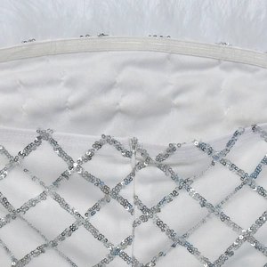 Detail of white dress showing silver sequin grid pattern and invisible zipper on fabric