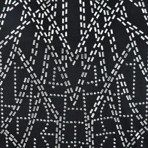 Dettaglio dei brillantini geometrici argento su tessuto a rete nero per vestito lungo